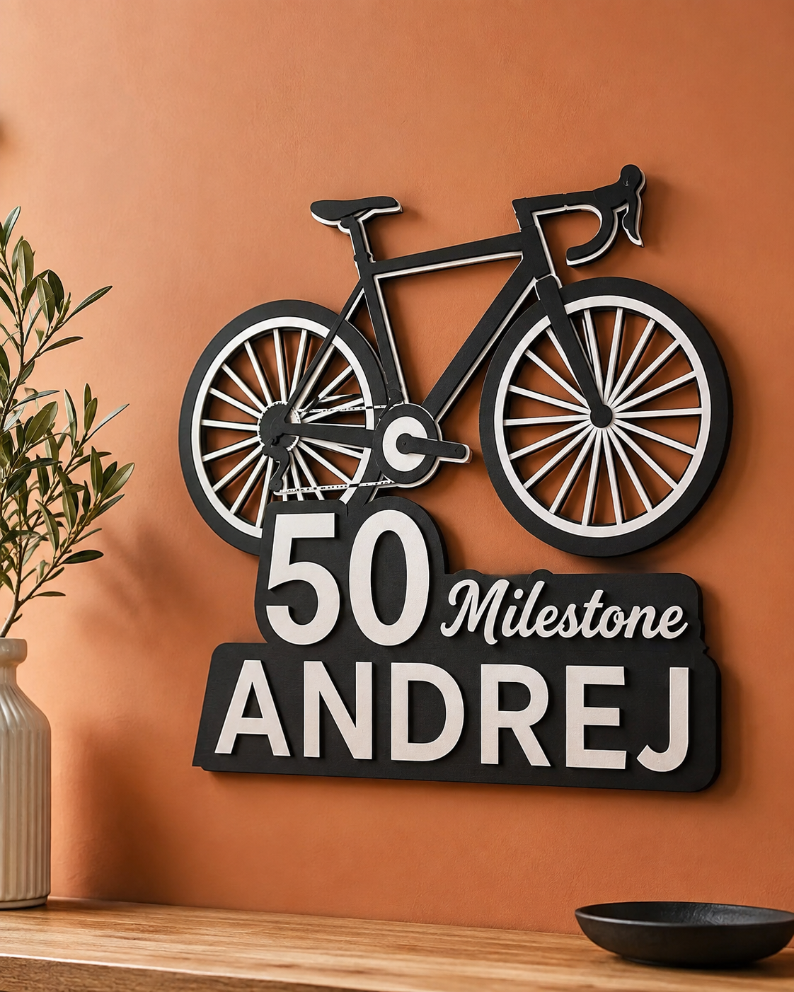 Črn lesen kolesar z napisom 50 Milestone Andrej na steni